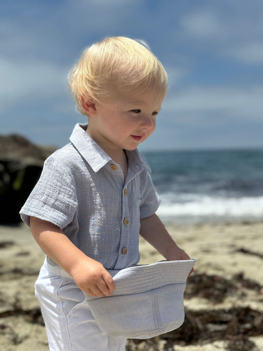 Child on a beach holding a hat with ocean and sky in the background