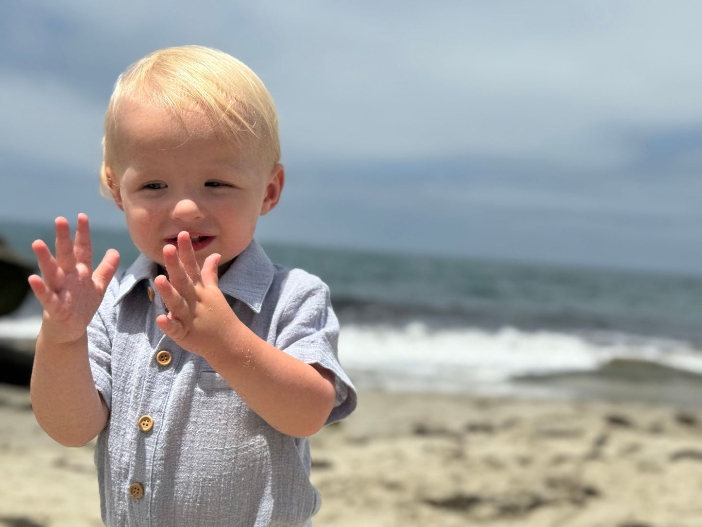 Child on a beach waving with ocean in the background