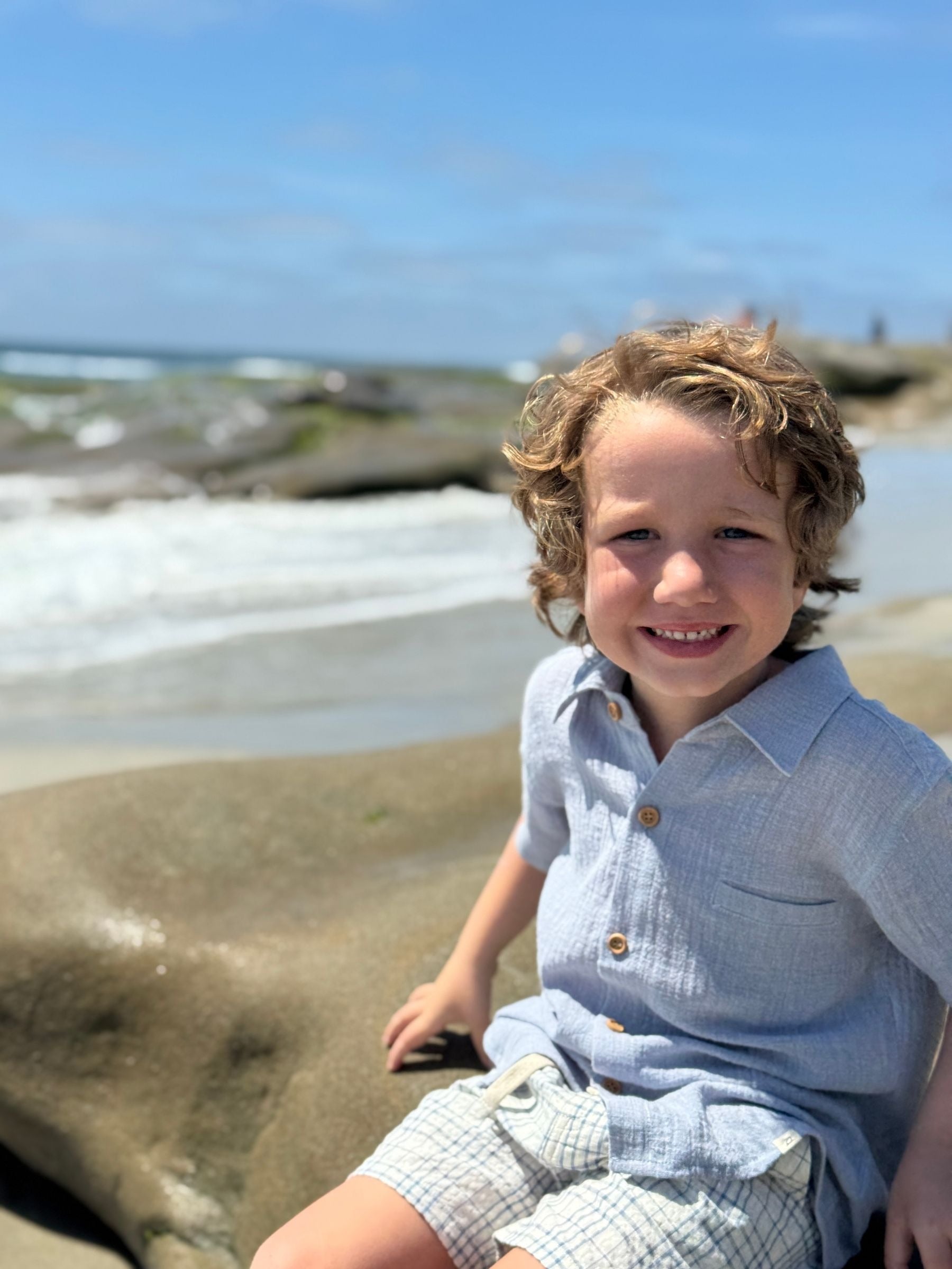 Child sitting on a beach with ocean waves in the background