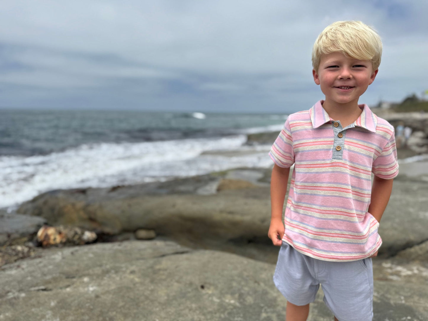 Young boy standing on a beach with ocean waves in the background