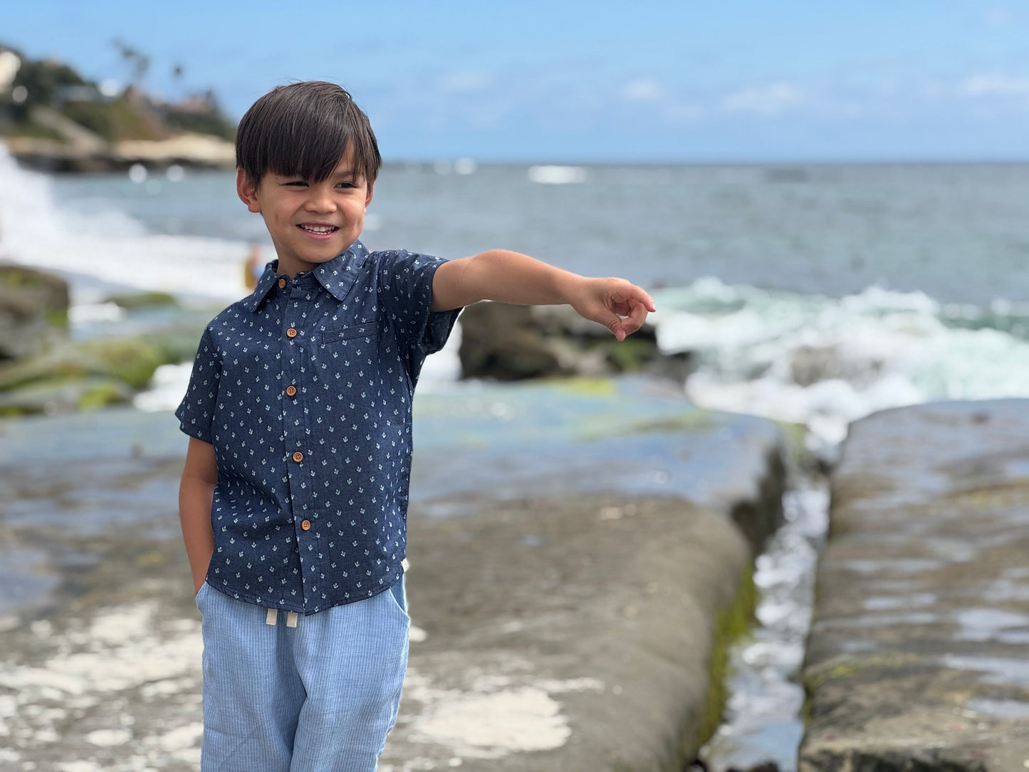 Child standing on a rocky beach with ocean waves in the background