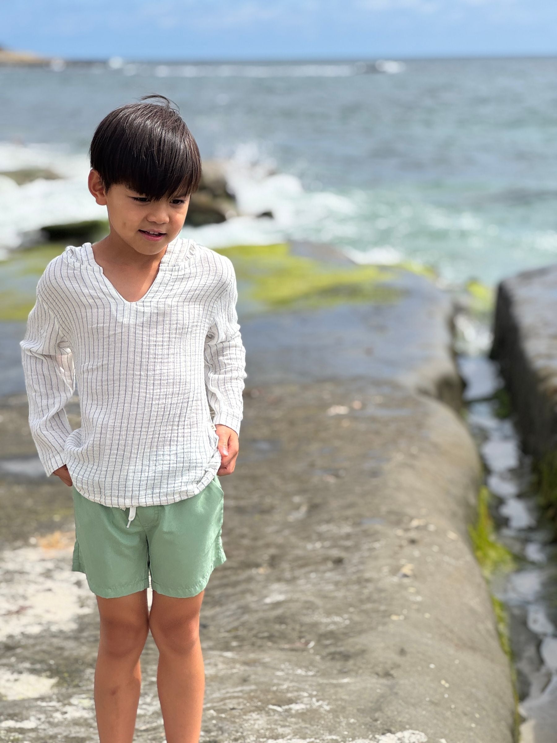 Child standing on a stone path by the ocean