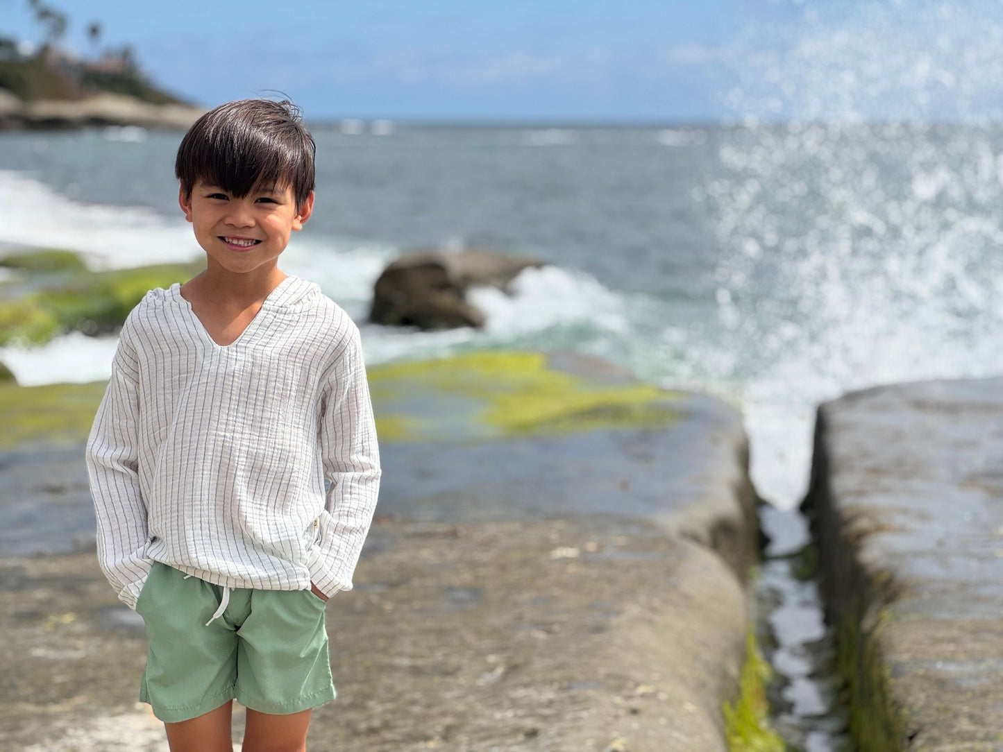 Child standing on a rocky beach with ocean waves in the background