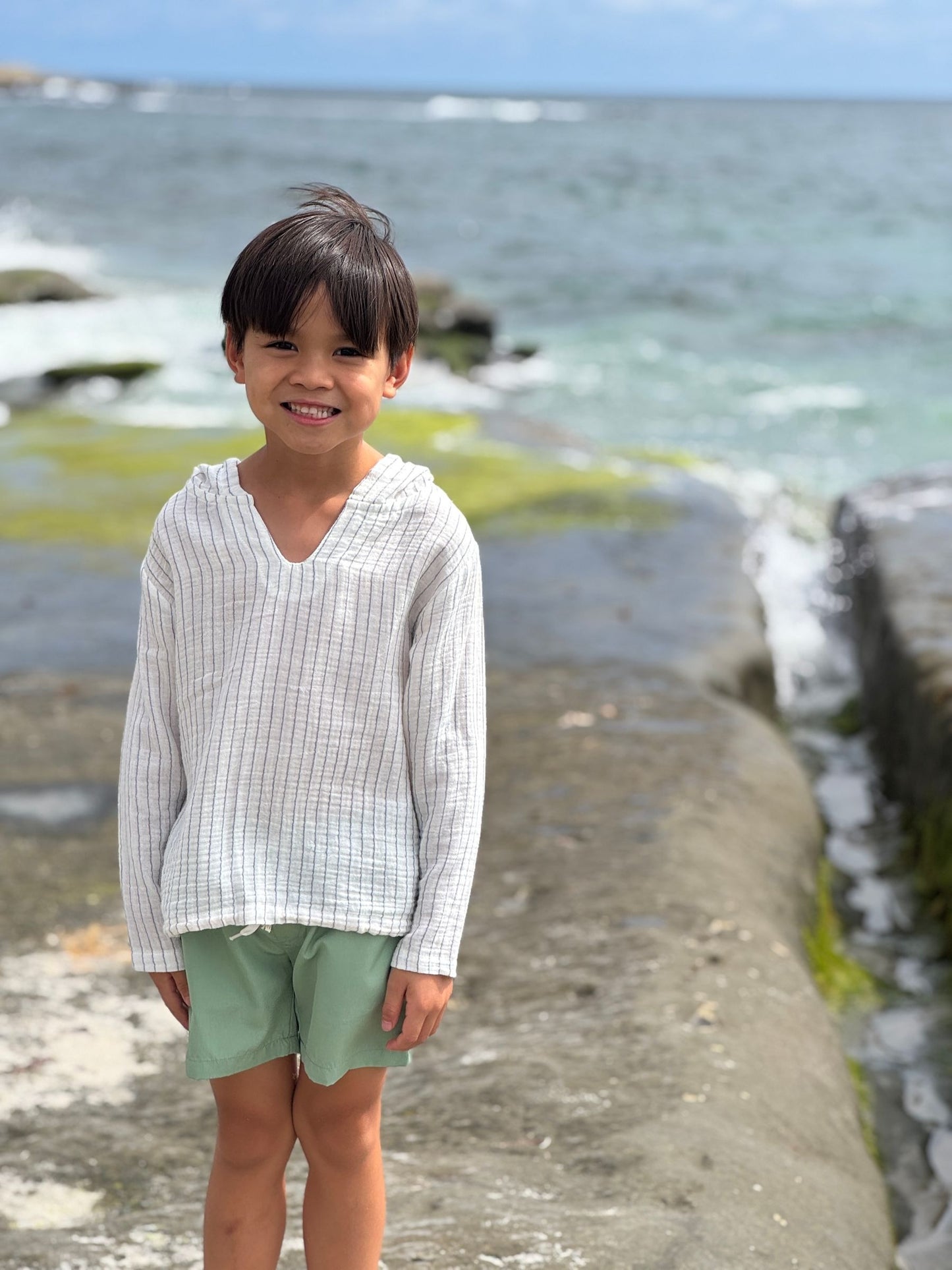 Child standing on a stone pathway by the ocean