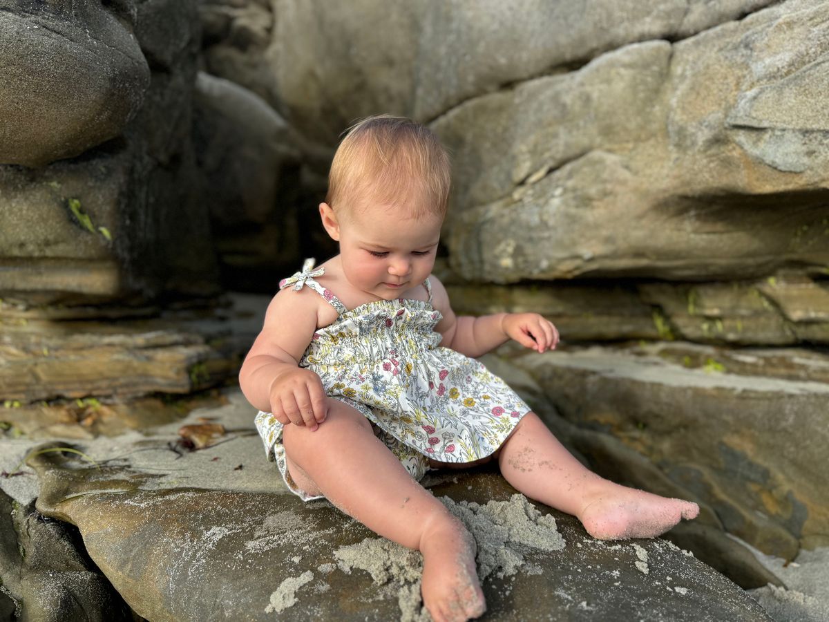 Baby sitting on rocks by a stone wall