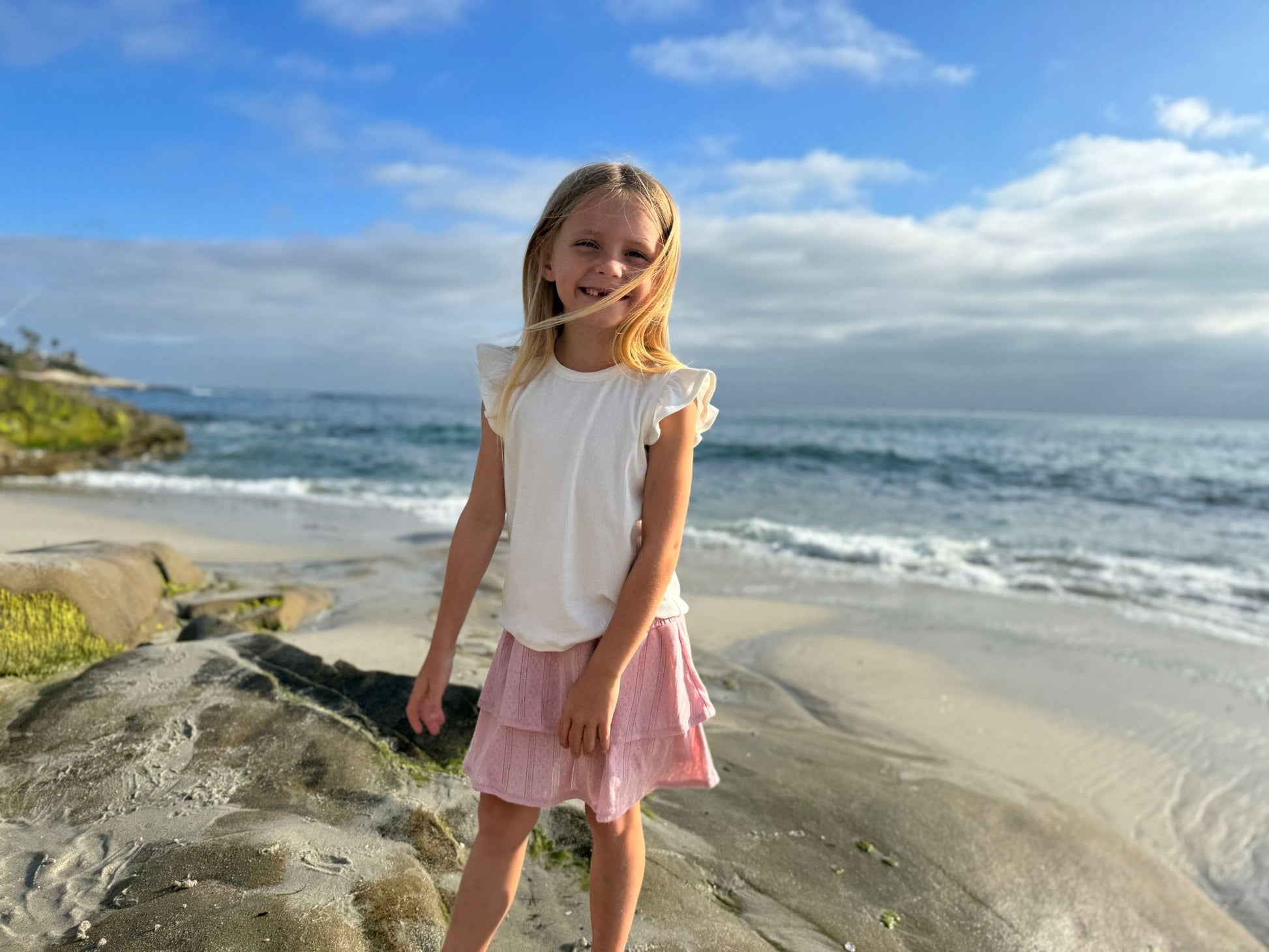 Young girl standing on a beach with ocean and sky in the background