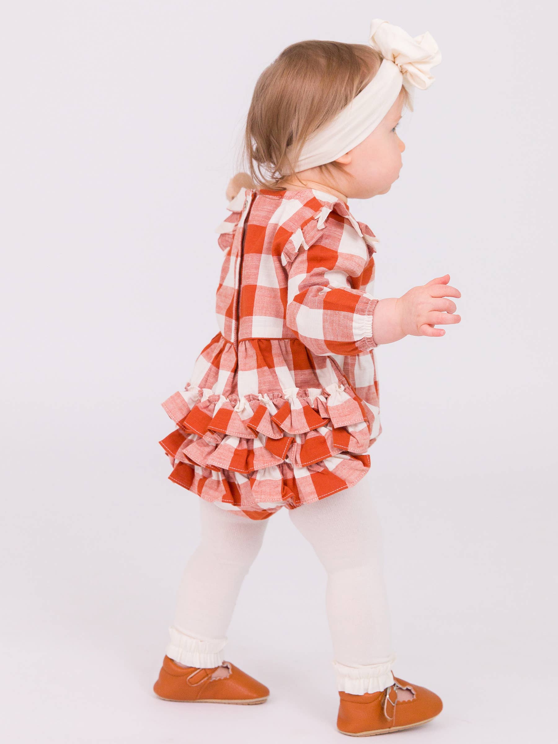 Child wearing a red and white checkered dress with ruffles on a white background